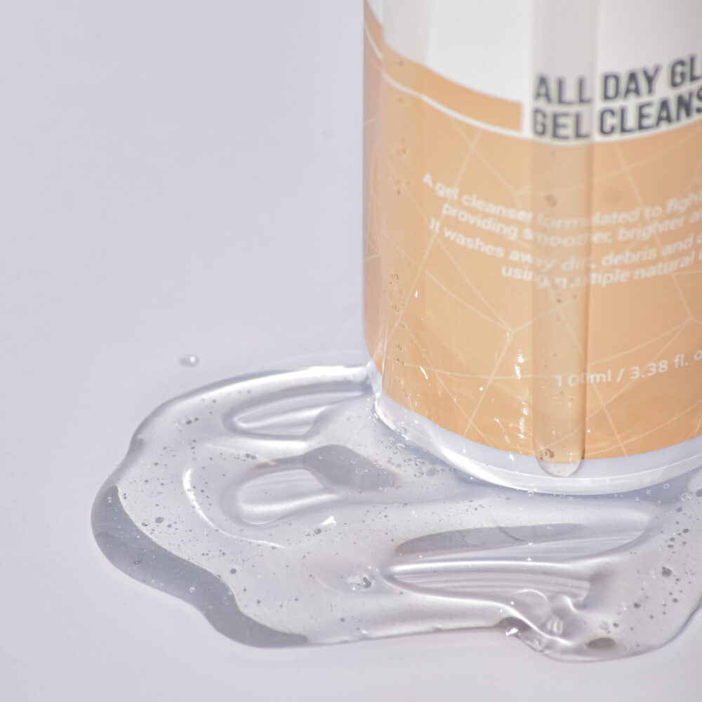 Nahaufnahme des KRX All Day Glow Gel Cleanser mit ausgelaufener Geltextur – Verpackung in weiß-goldenem Design.