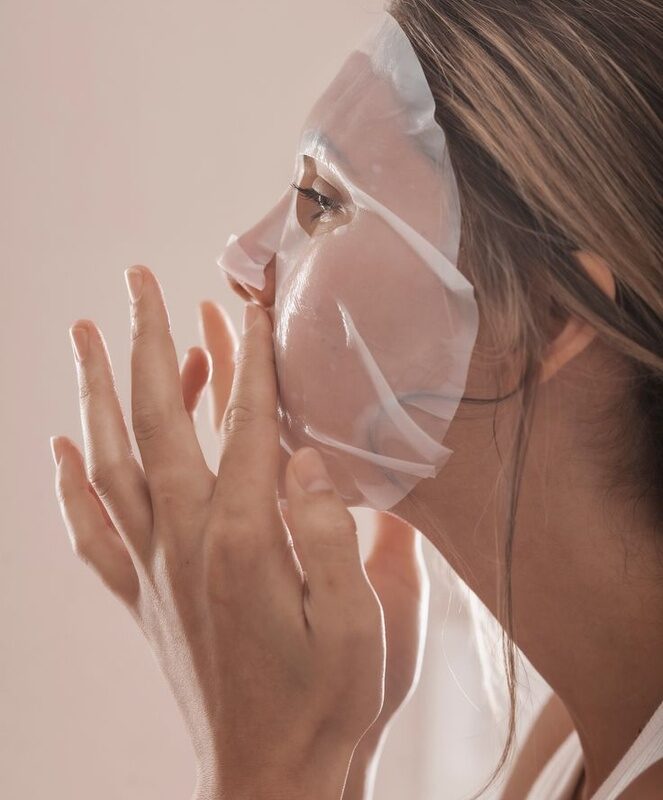 Frau legt eine Exosome Sheet Mask auf ihr Gesicht – für intensive Hautpflege.